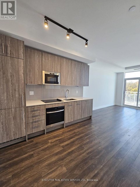 A modern kitchen with wooden cabinets and a microwave built into the cabinetry.