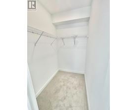 A white bedroom with a carpeted floor and a metal rack on the wall.
