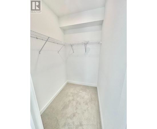 A white bedroom with a carpeted floor and a metal rack on the wall.
