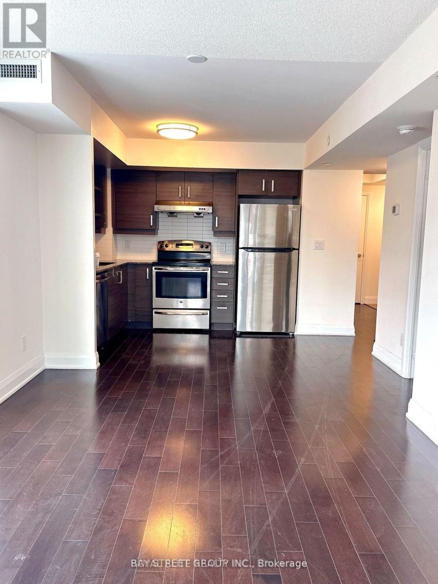 A kitchen with a refrigerator, oven, and stove.