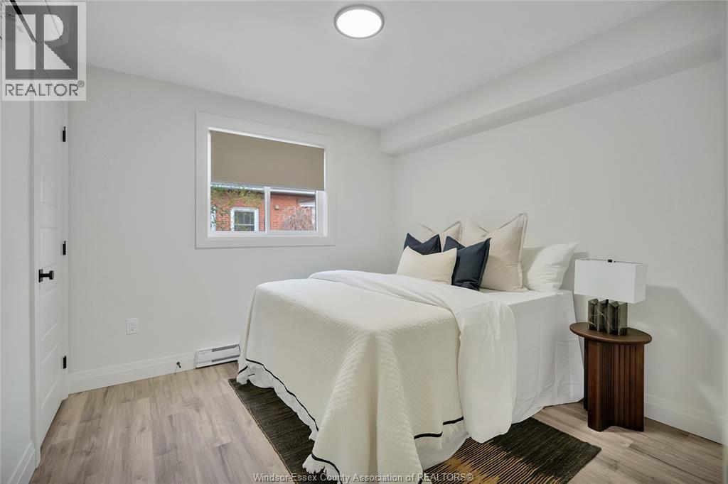 A bedroom with a white bed and a small table with a lamp.