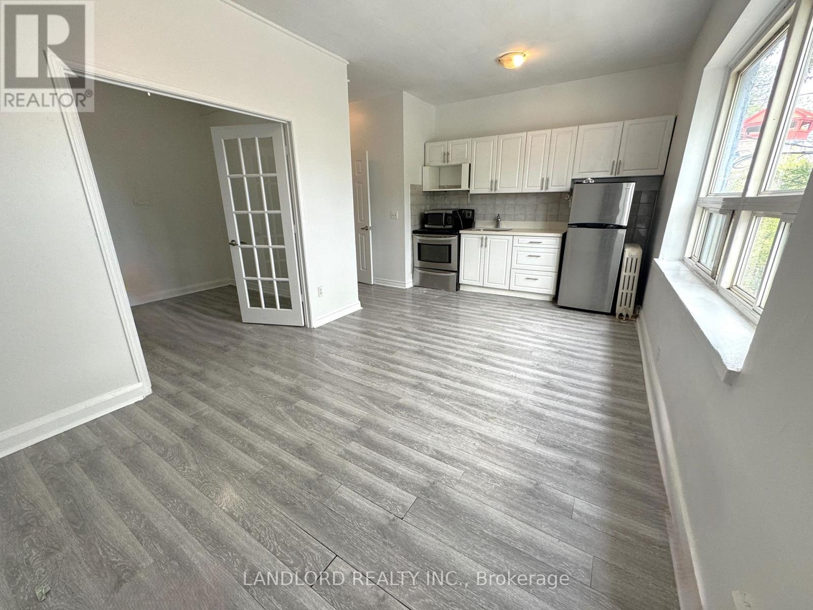A spacious kitchen with white cabinets and a refrigerator.