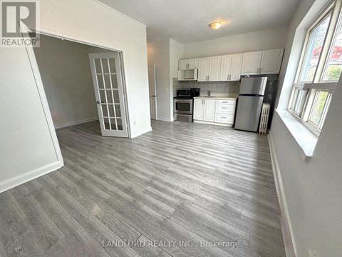 A spacious kitchen with white cabinets and a refrigerator.