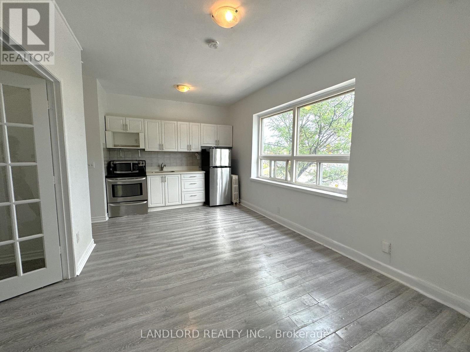A kitchen with white cabinets and a refrigerator.