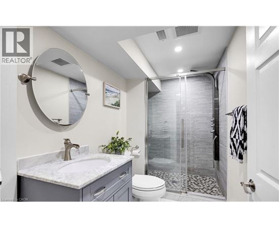 A bathroom with a white sink and a round mirror.