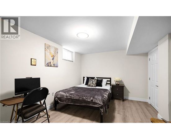 A bedroom with a bed, chair, and a painting on the wall.