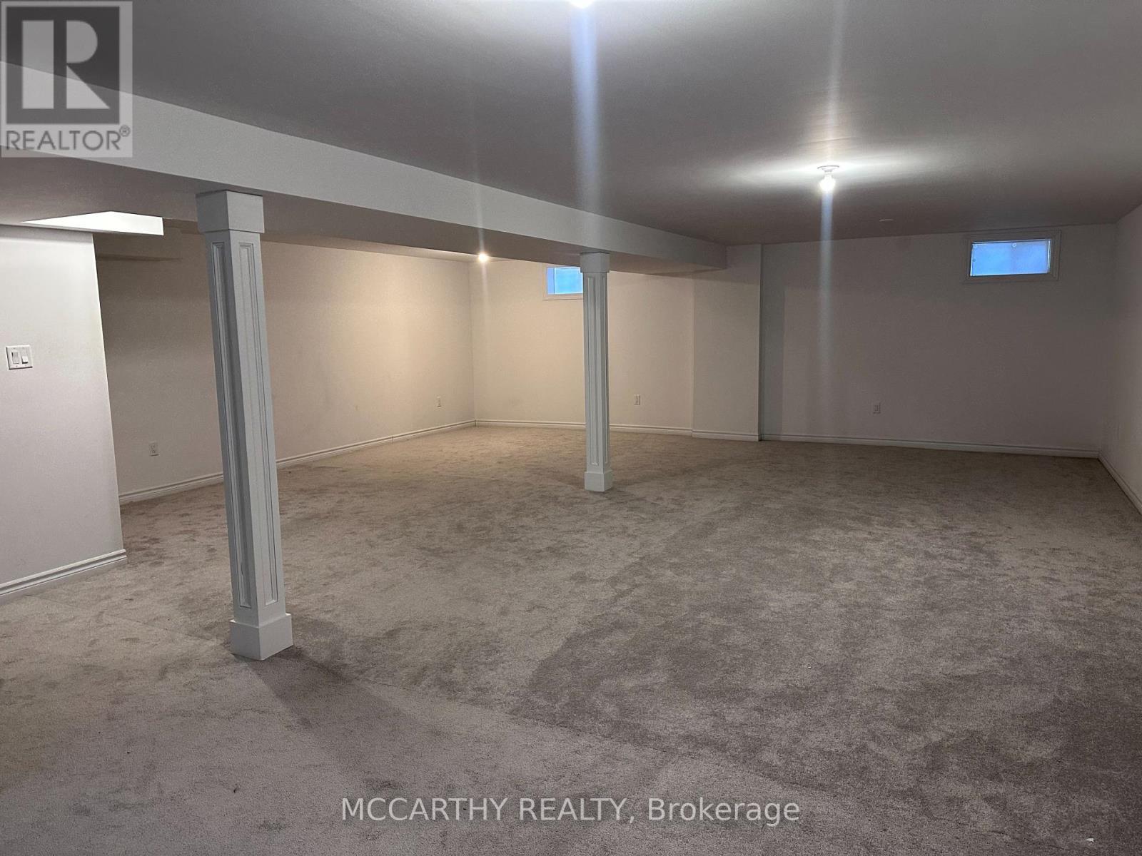 A spacious room with a carpeted floor and pillars at the corners.