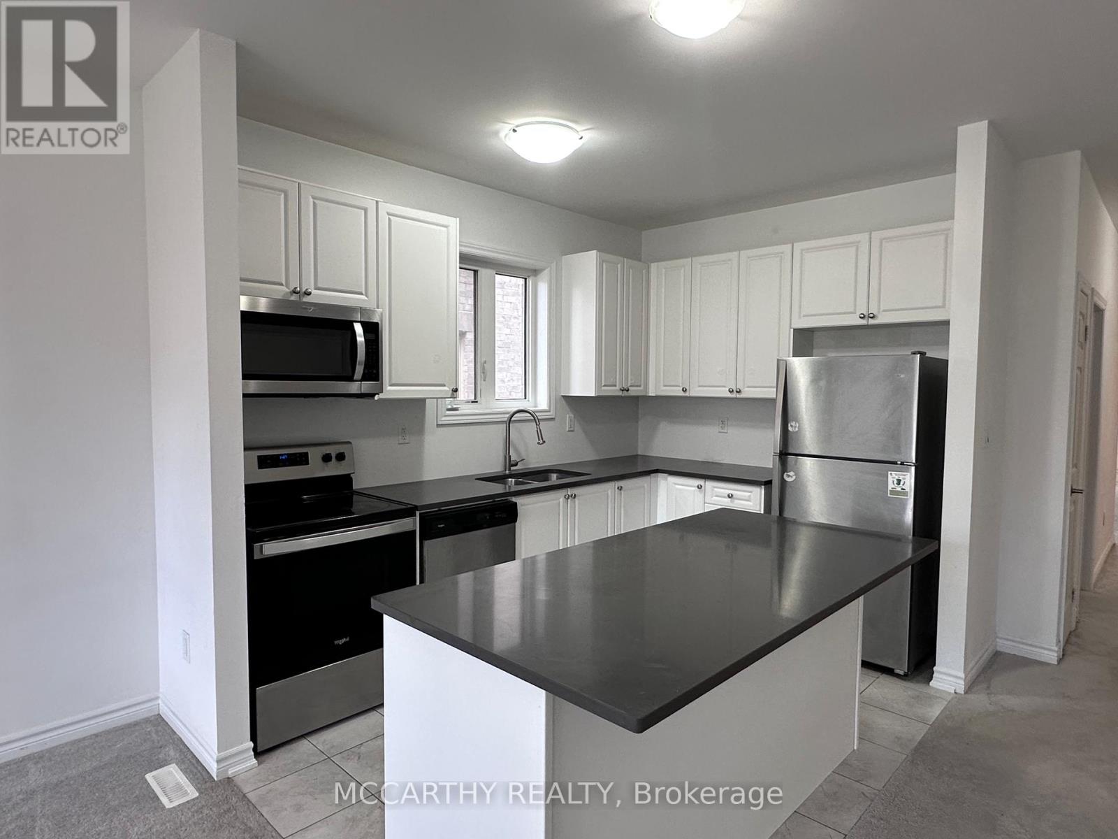 A kitchen with a black counter top and stainless steel appliances.
