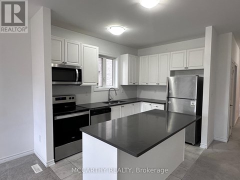 A kitchen with a black counter top and stainless steel appliances.