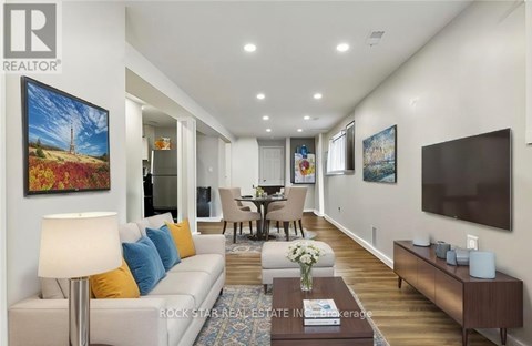 A living room with a white couch and a painting on the wall.