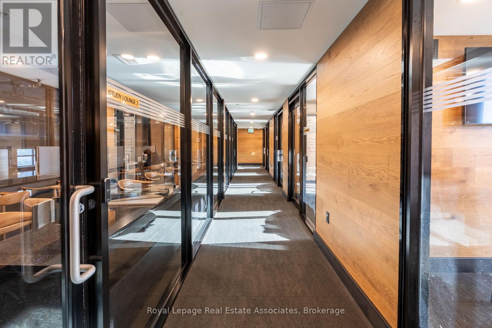 A hallway with a glass door on the left and wooden doors on the right.