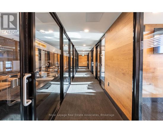 A hallway with a glass door on the left and wooden doors on the right.