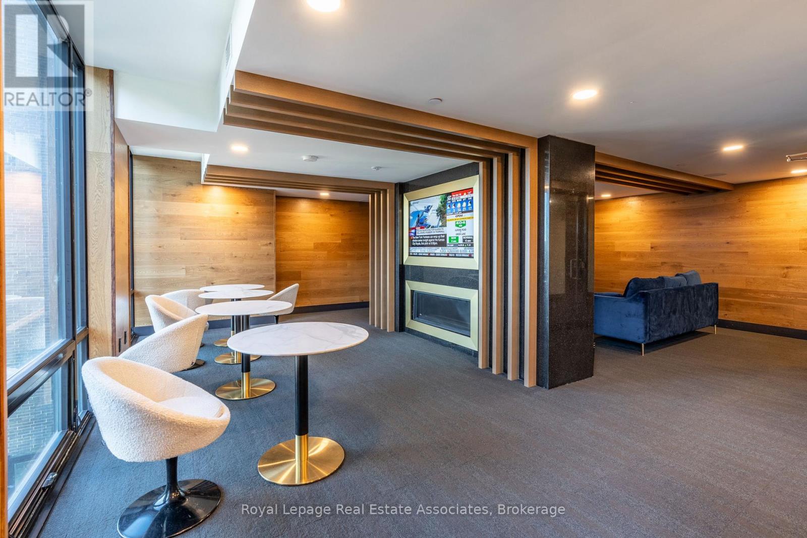 A modern office space with a wood panelled wall and a television screen.