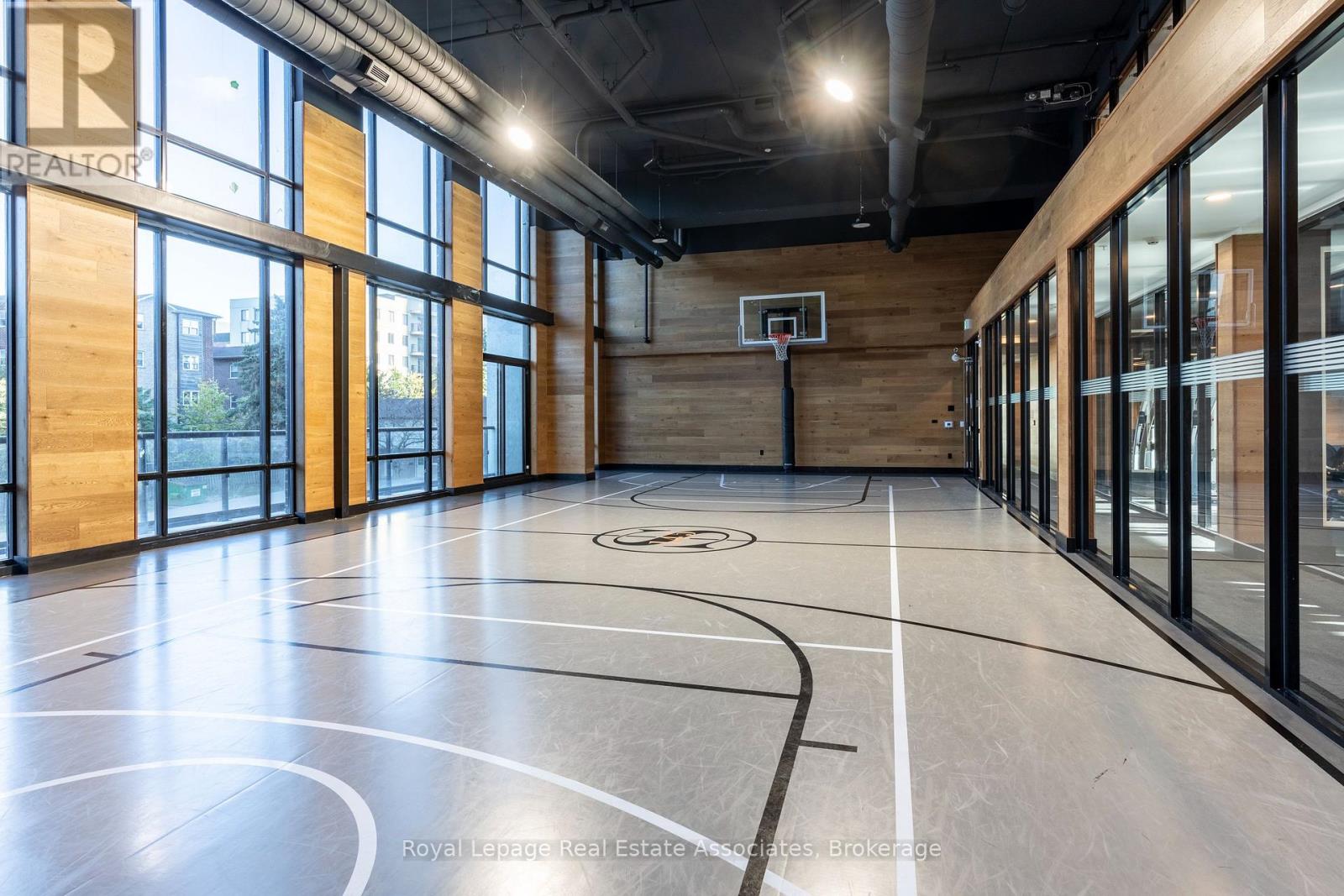 A basketball court inside a building with a wooden floor and a basketball hoop.