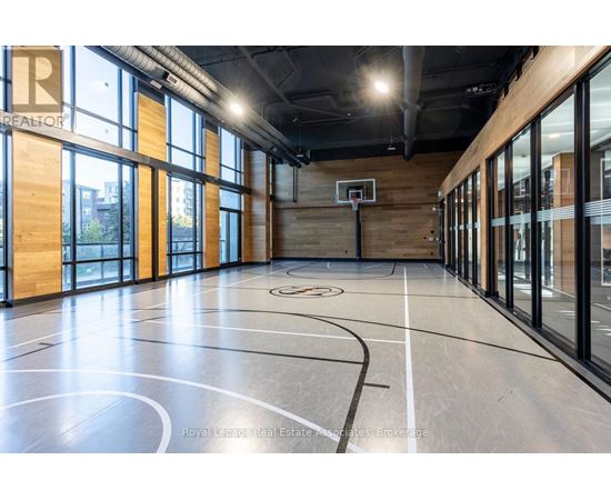 A basketball court inside a building with a wooden floor and a basketball hoop.