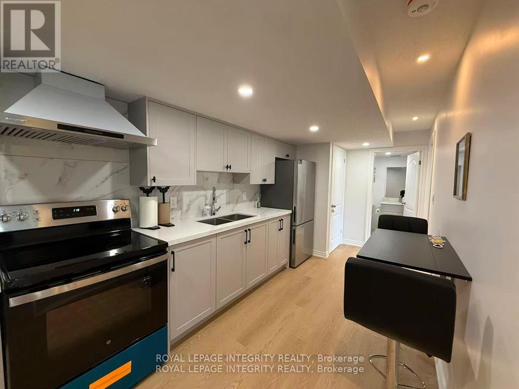 A modern kitchen with a black stove top oven and white cabinets.
