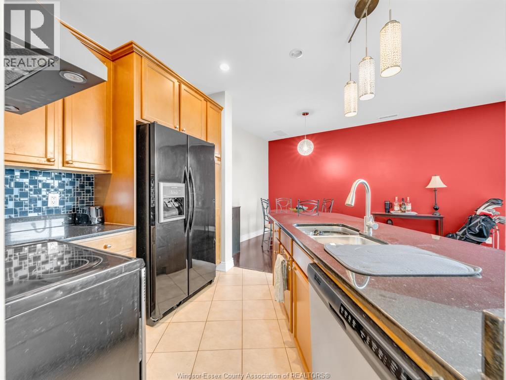 A kitchen with a black refrigerator and a red wall.