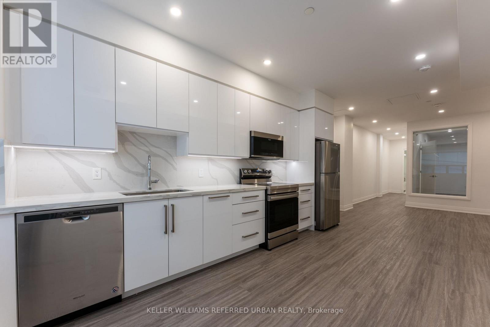 A modern kitchen with stainless steel appliances and white cabinetry.