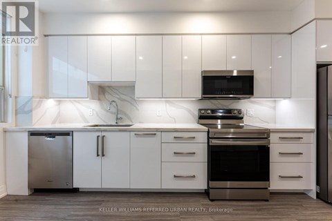 A modern kitchen with white cabinets and stainless steel appliances.