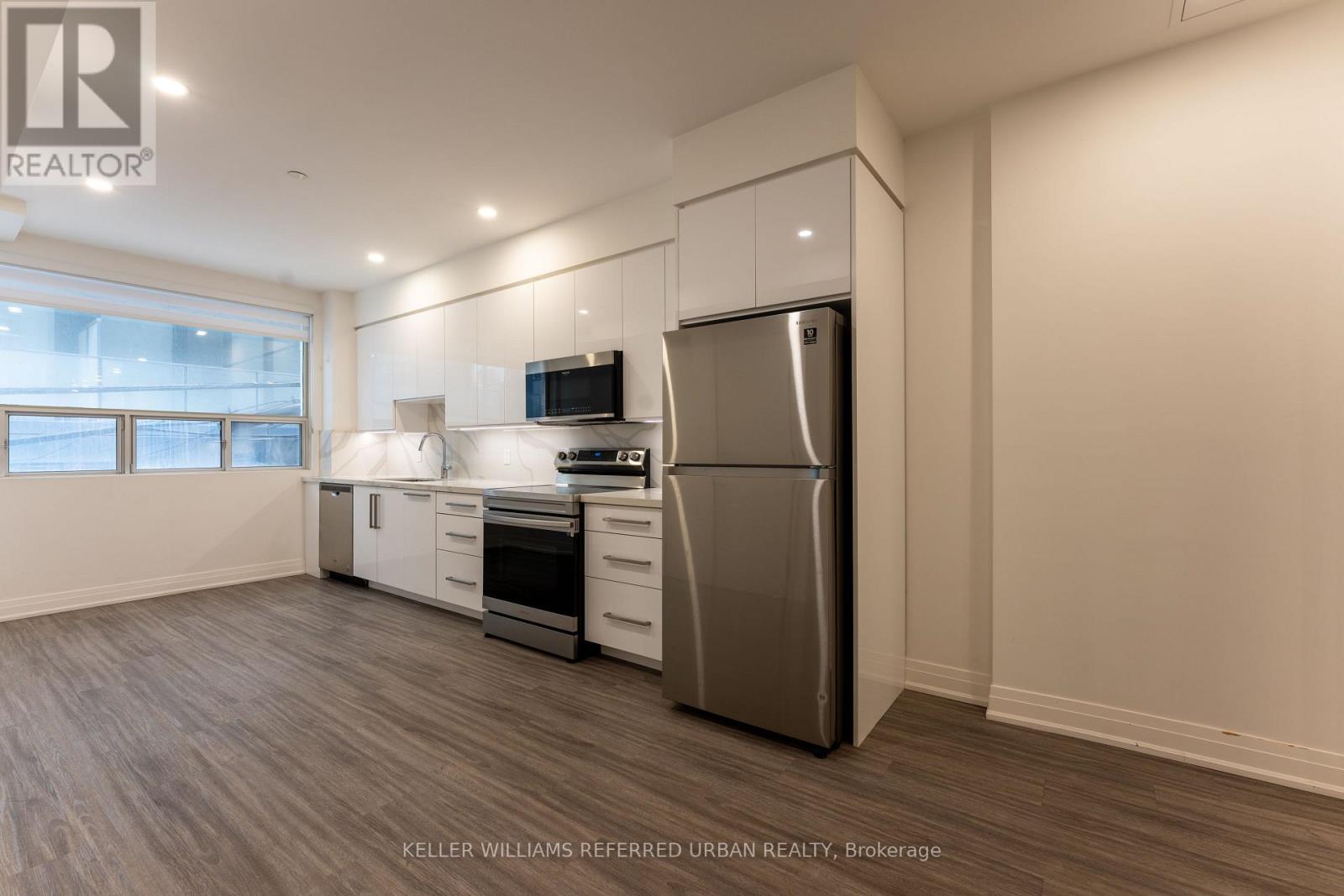 A well-lit kitchen with a refrigerator, oven, and microwave.
