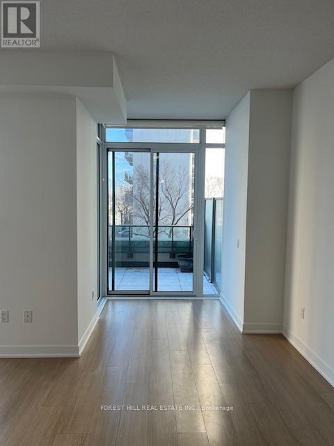 A spacious room with a large window and wooden flooring.