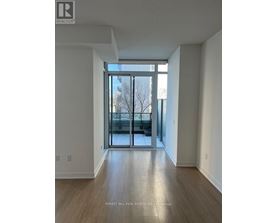 A spacious room with a large window and wooden flooring.