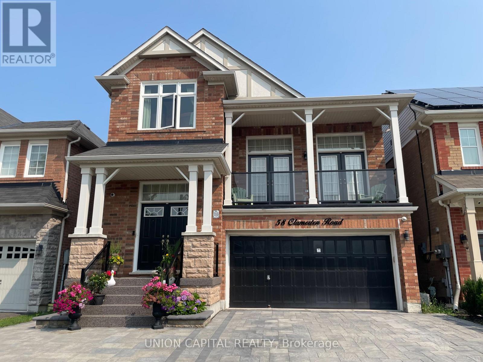 A large brick house with a black garage door and a sign that says "St. Clements Road.".