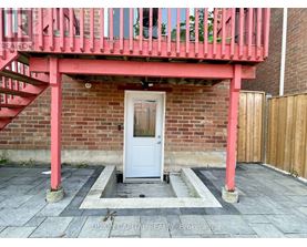 A white door is in a brick wall with a red railing above it.