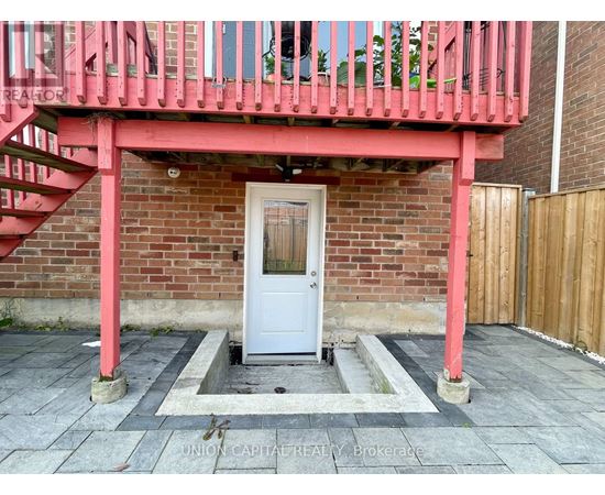 A white door is in a brick wall with a red railing above it.