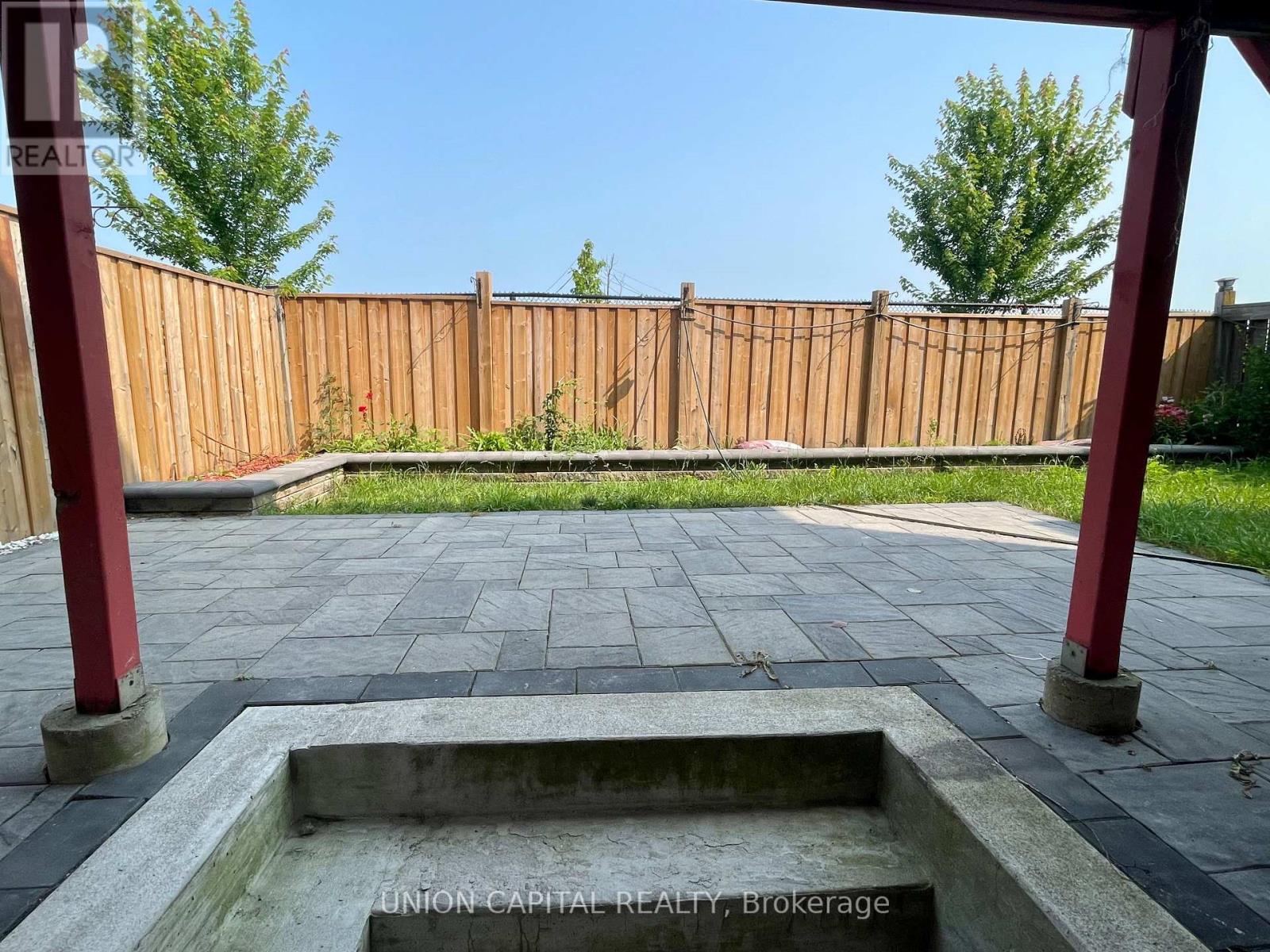 A backyard with a wooden fence and a concrete fire pit.