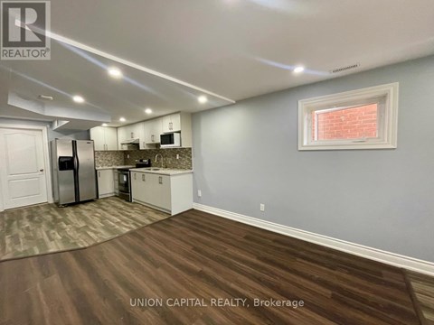 A kitchen with wood flooring and a window with blinds.