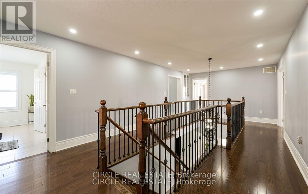 A spacious hallway with a wooden staircase and a black railing.
