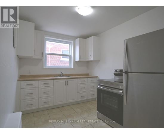 A kitchen with white cabinets and a black refrigerator.