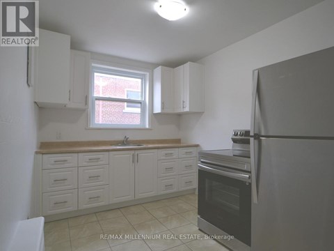 A kitchen with white cabinets and a black refrigerator.