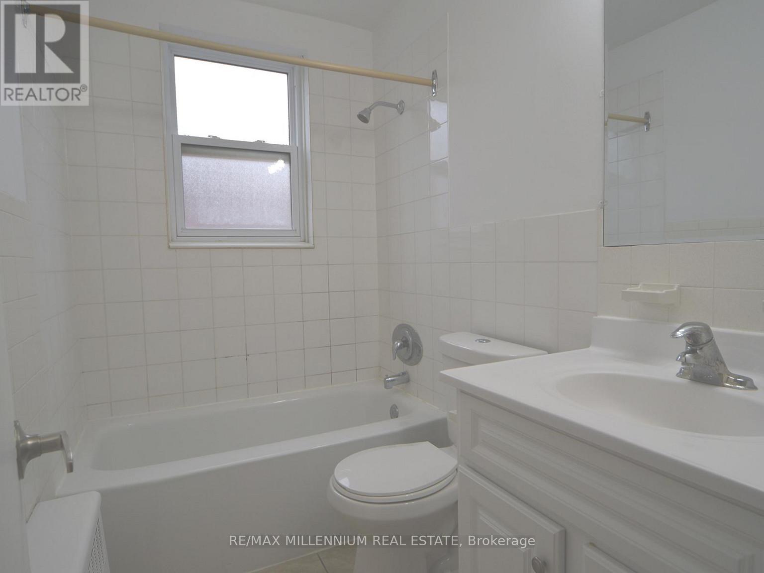 A white bathroom with a toilet, sink, and tub.