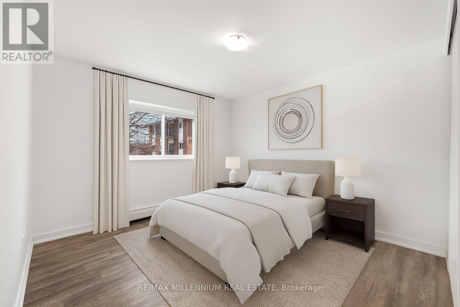 A bedroom with a large bed and a window with curtains.