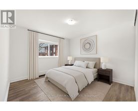 A bedroom with a large bed and a window with curtains.