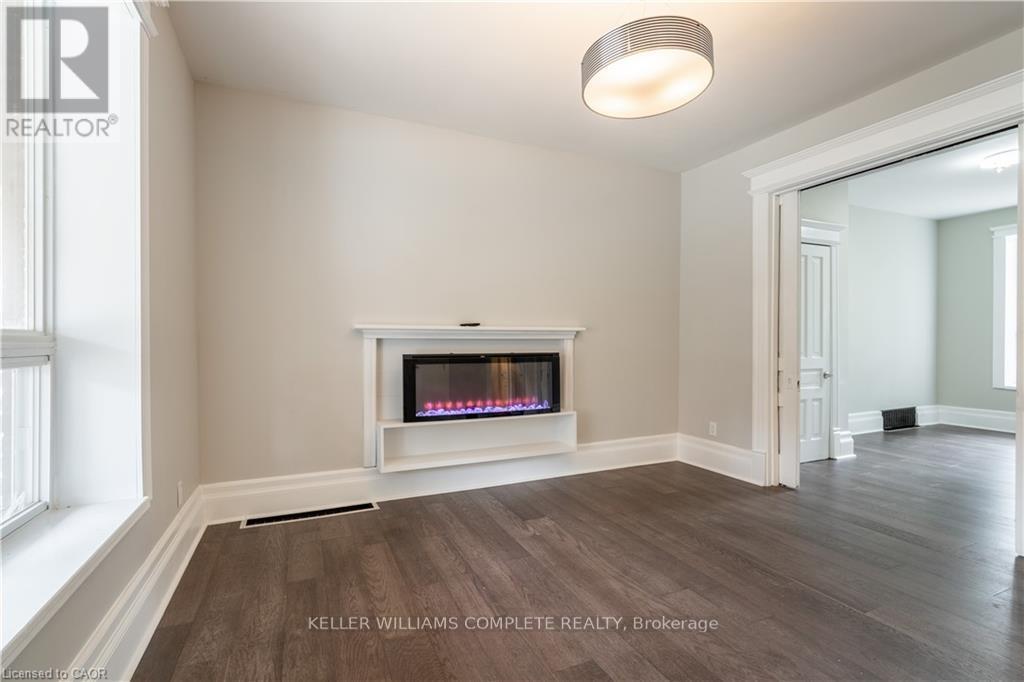 A spacious room with a fireplace and wood flooring.