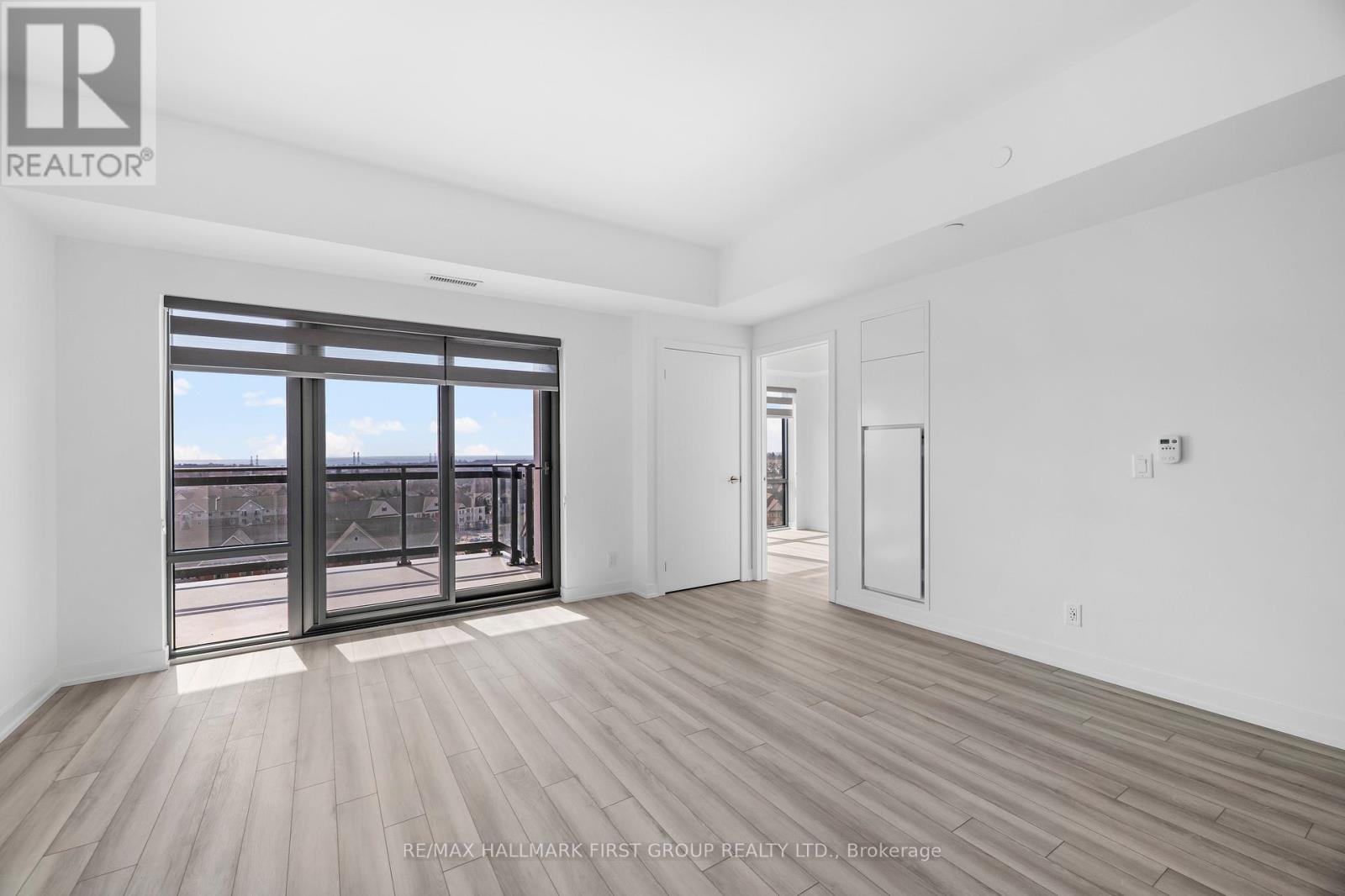A spacious room with wooden flooring and a large window overlooking a cityscape.