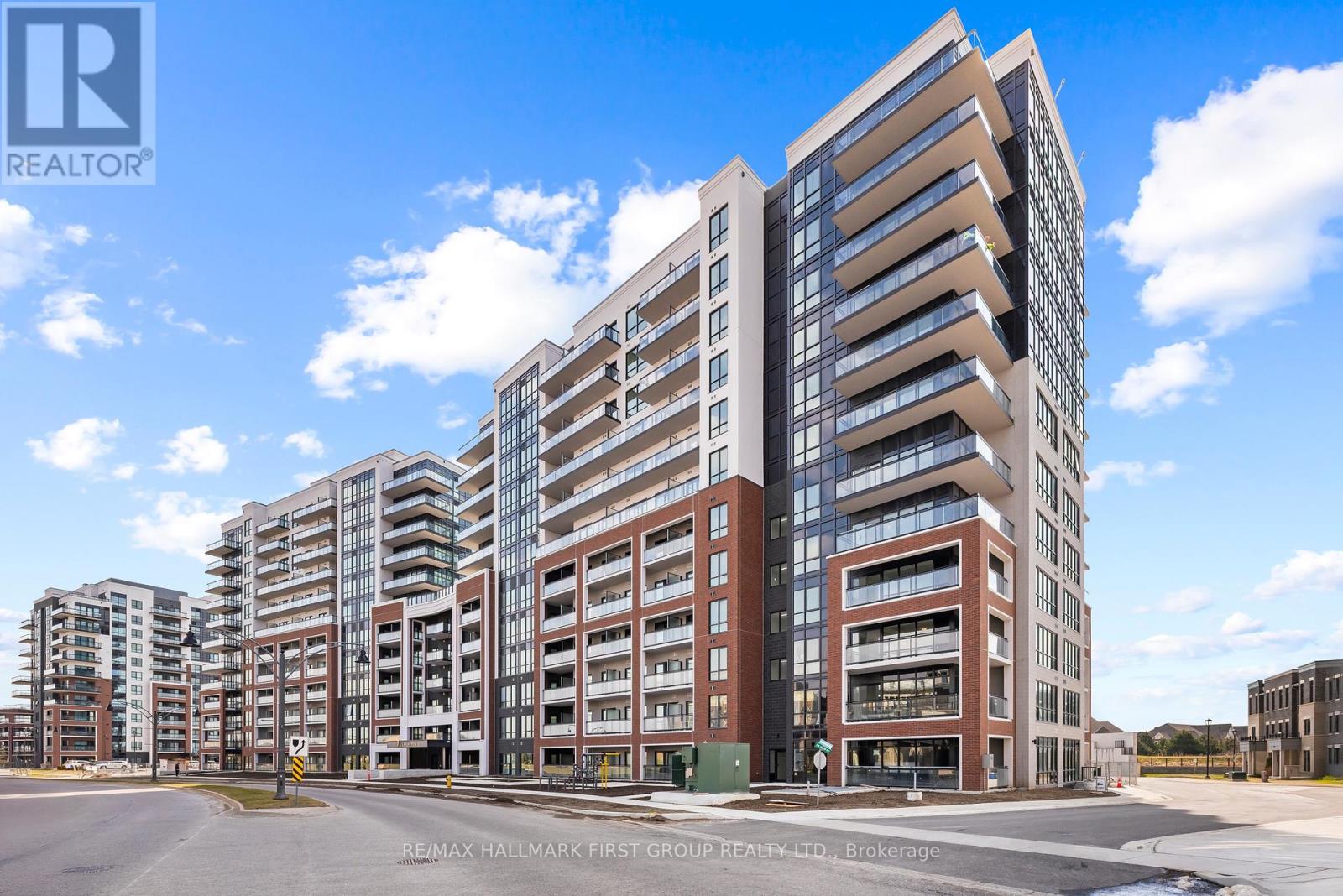 A large, modern multi-story building with a glass facade and a parking lot in front.
