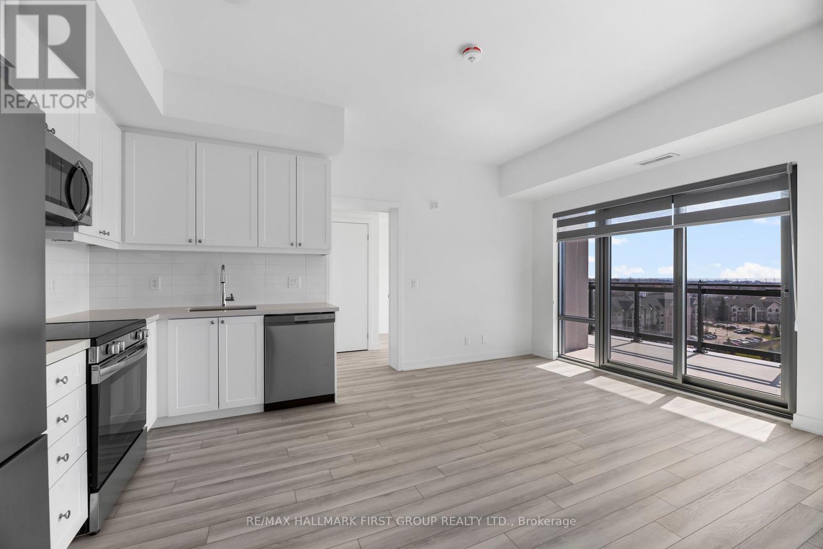 A spacious kitchen with white cabinets and a view of the city through the windows.
