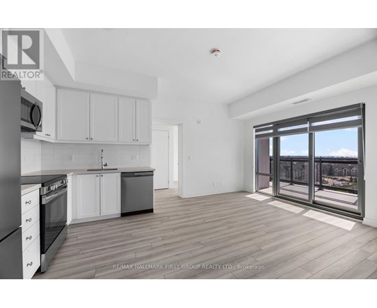 A spacious kitchen with white cabinets and a view of the city through the windows.