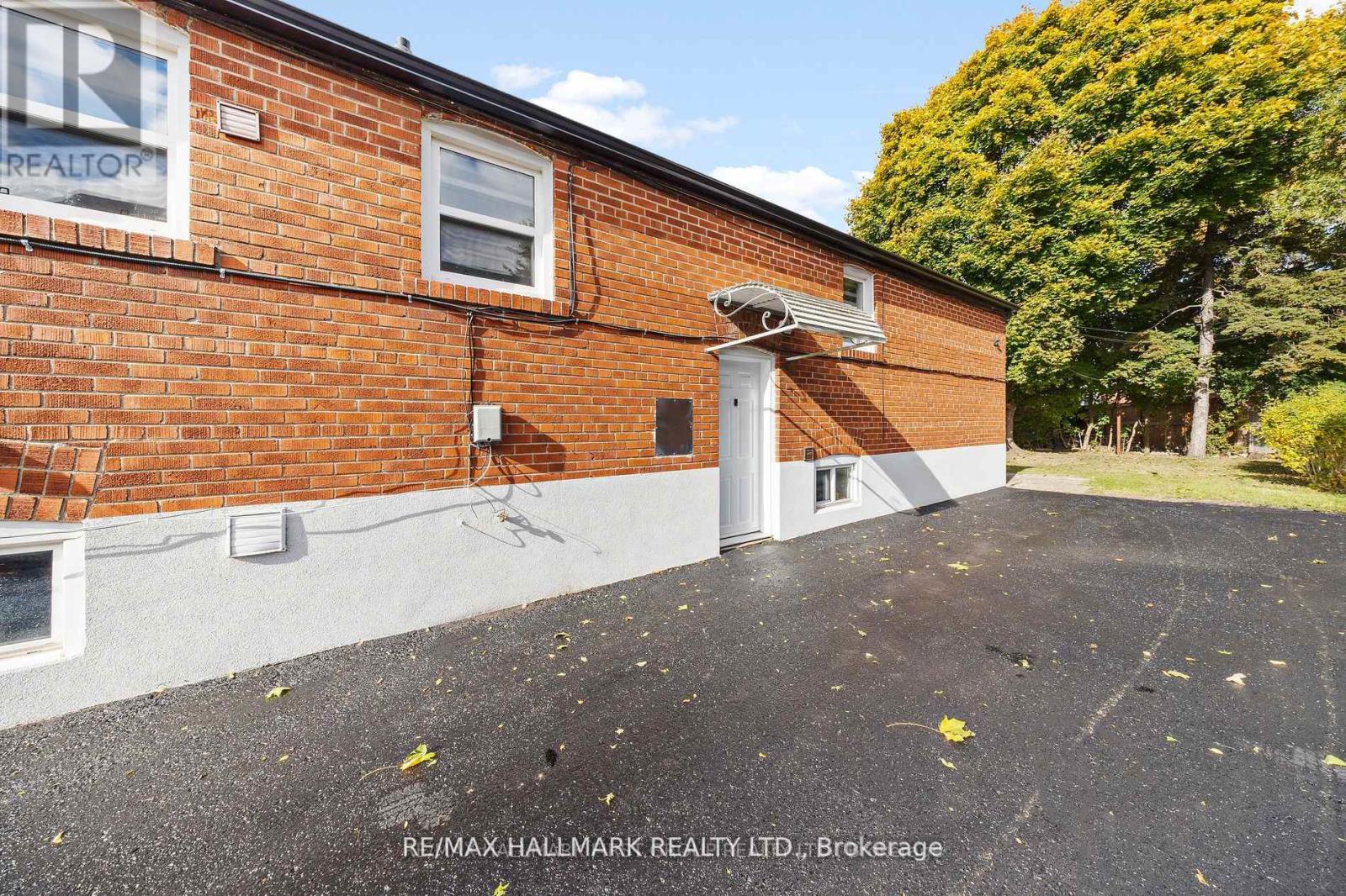 A red brick building with a white door and a sign that says RE/MAX HALLMARK REALTY, LTD., Brokerage.