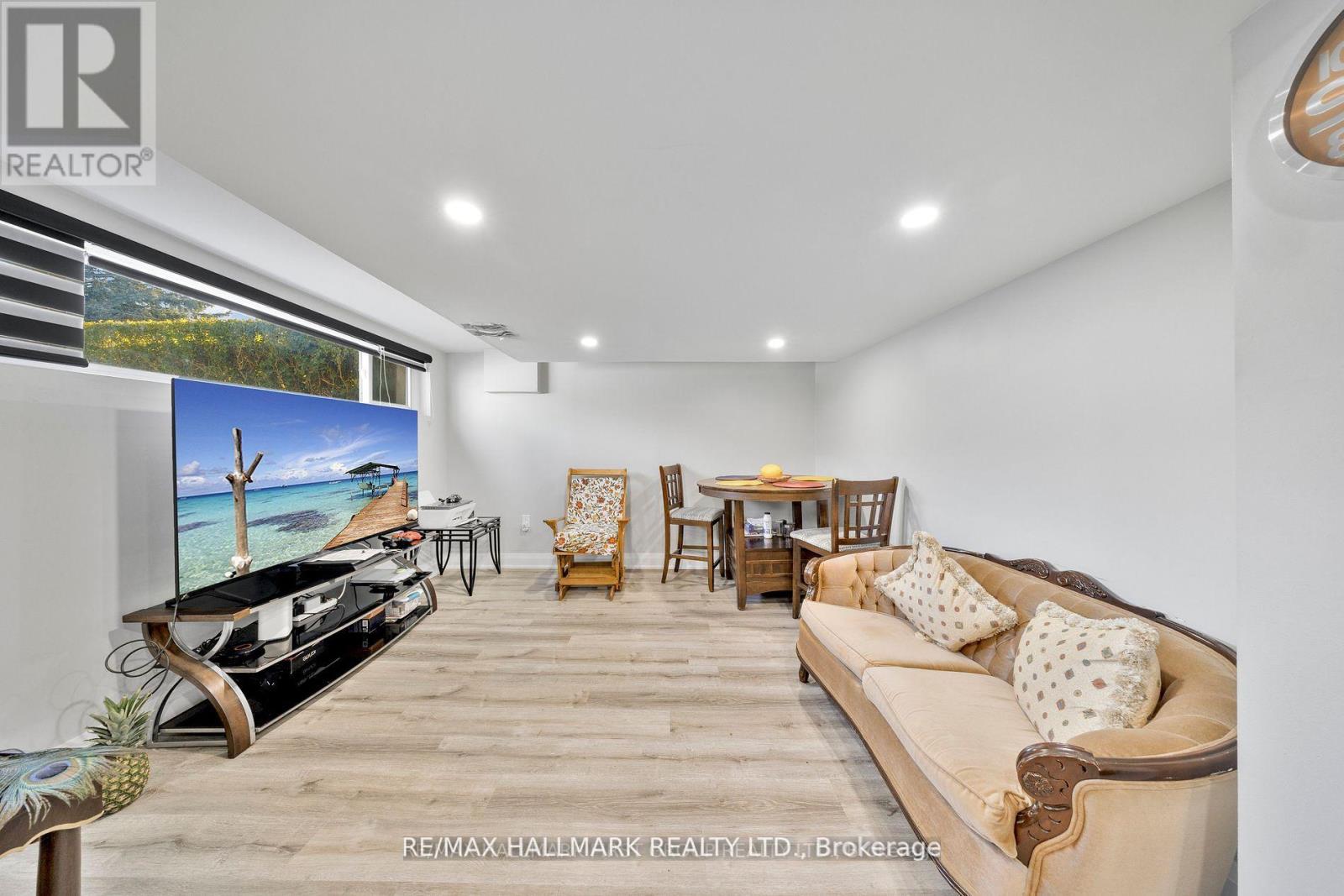 A living room with a couch, chairs, and a television.
