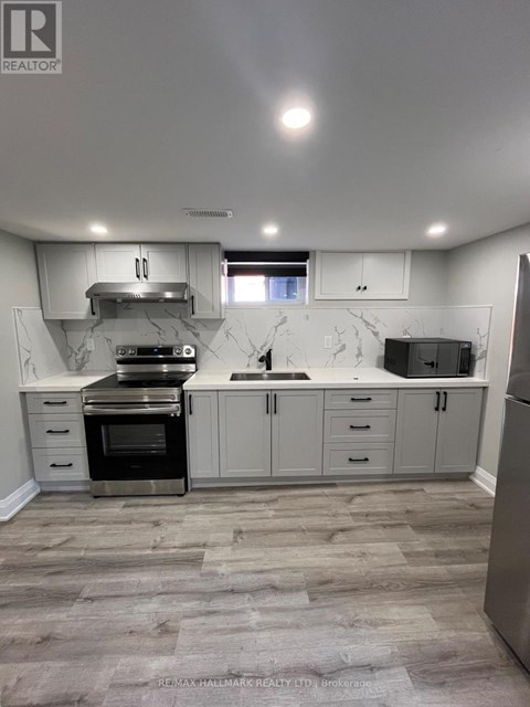 A kitchen with a refrigerator, oven, and sink.