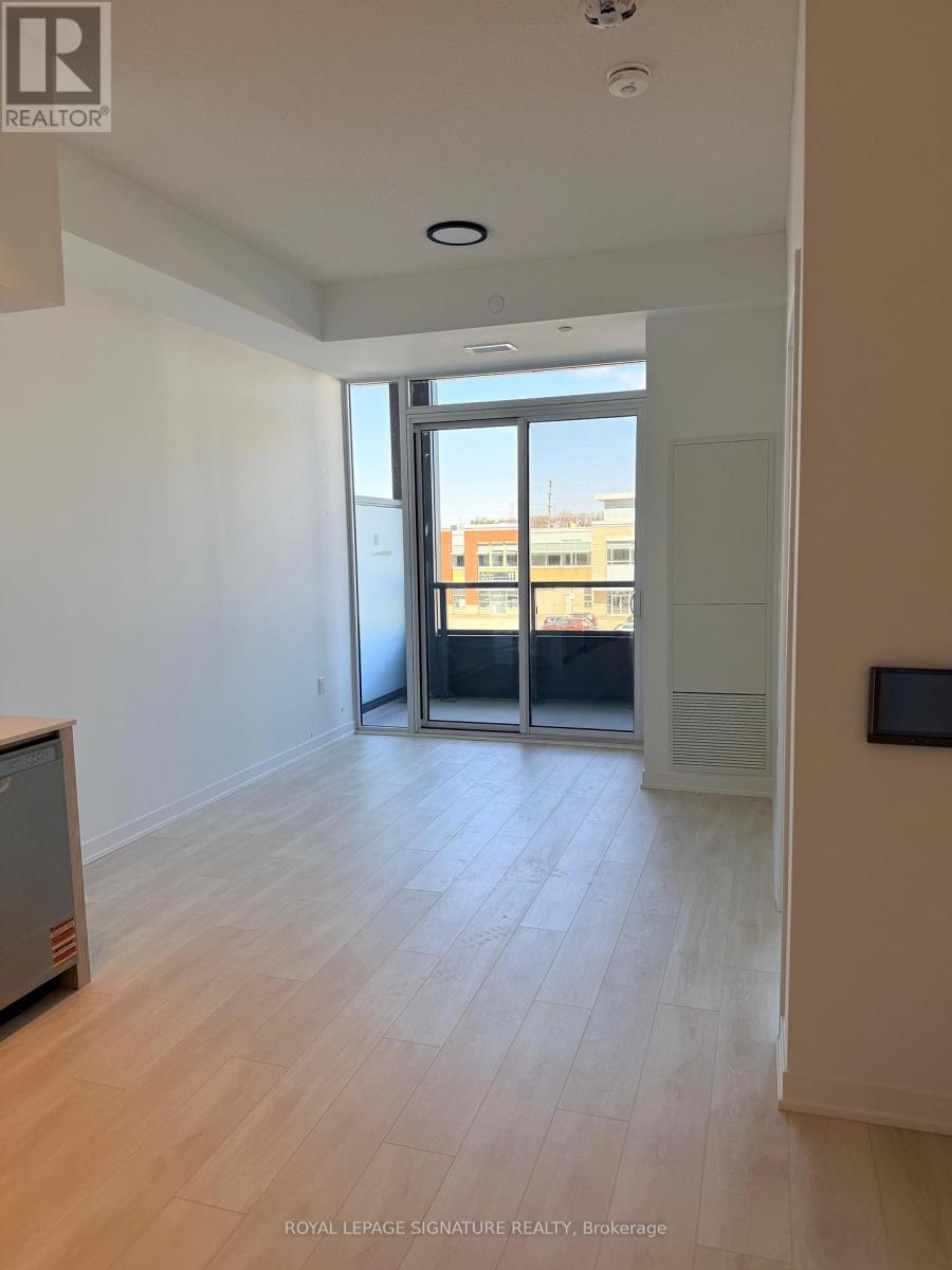 A spacious room with wooden flooring and a sliding glass door leading to a balcony.