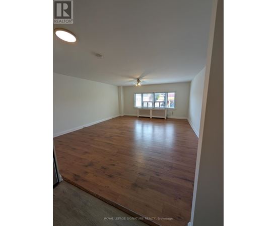 A room with wooden flooring and a window with blinds.