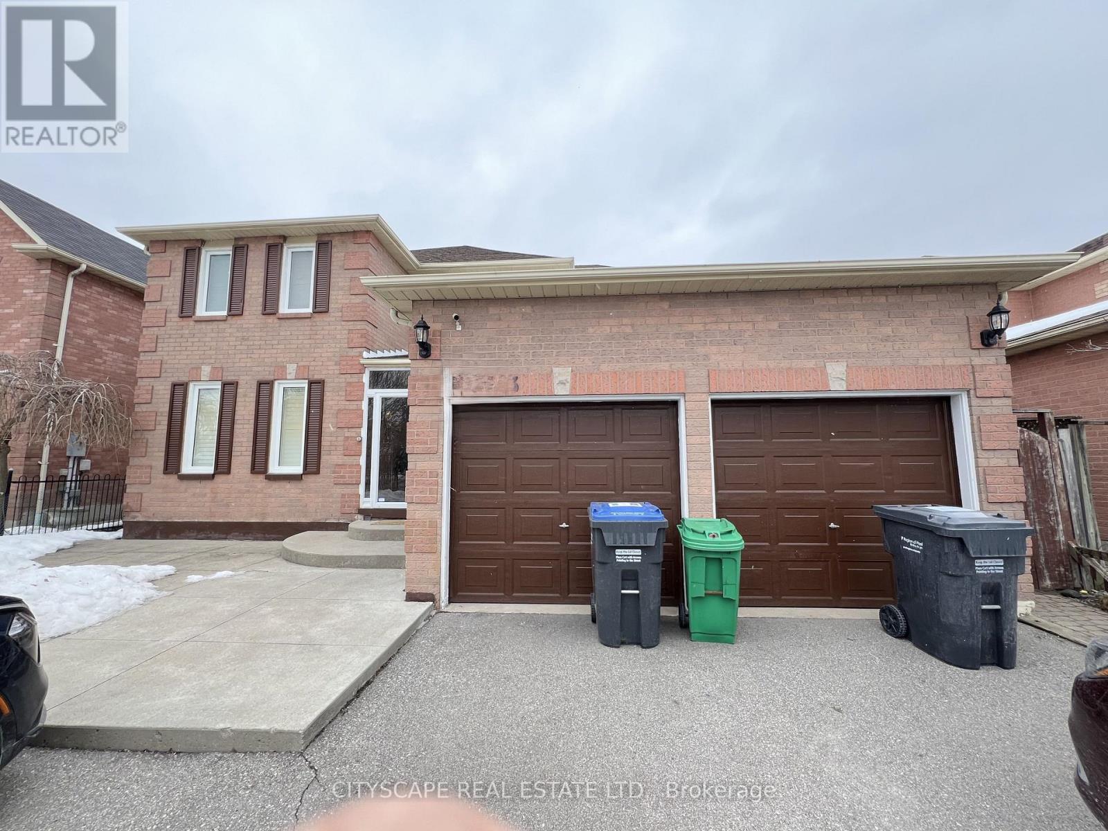 A house with a brown garage door and two trash bins in front.