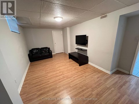 A living room with a black couch and a television on a stand.
