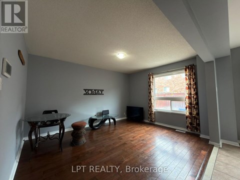 A living room with a glass table and chairs, a flat screen TV, and a window with curtains.